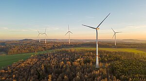 Fünf Windräder in Waldstandorten in der Morgendämmerung.
